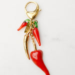 Red chili pepper charm with gold accents on a white background