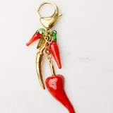 Red chili pepper charm with gold accents on a white background